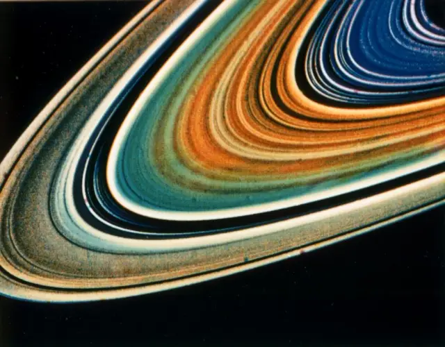 Voyager image of Saturn's rings in bands of orange, teal, cream, and blue against black space